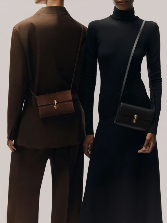 Two models wearing tailored brown and black outfits, each wearing a small rectangular leather crossbody bag with a gold clasp.