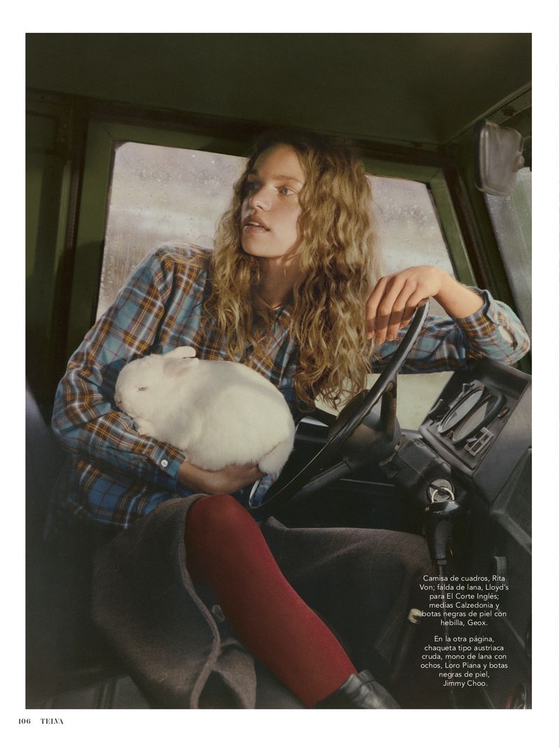 A woman with long wavy hair and a plaid shirt holds a white rabbit inside a vehicle, creating a unique and captivating portrait.