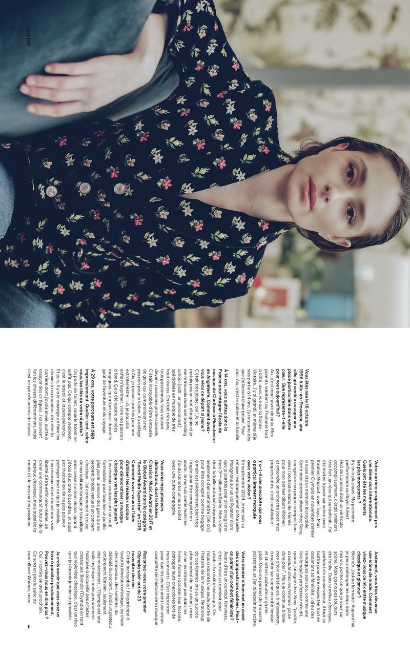A woman in a floral jacket lounges on a teal sofa in a close-up shot, capturing a relaxed, indoor editorial portrait.