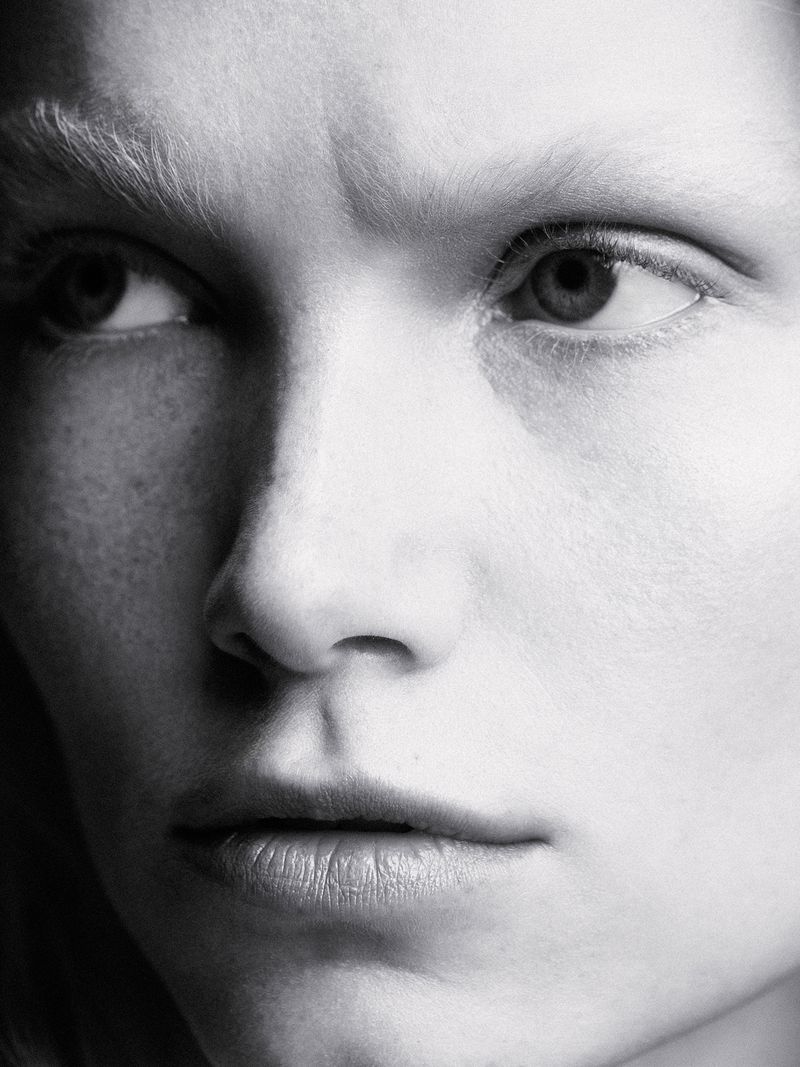 Close-up black and white portrait of an adult female with fair skin, looking off to the left with serious expression in studio lighting.