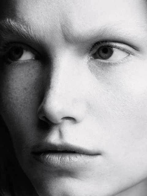 Close-up black and white portrait of an adult female with fair skin, looking off to the left with serious expression in studio lighting.