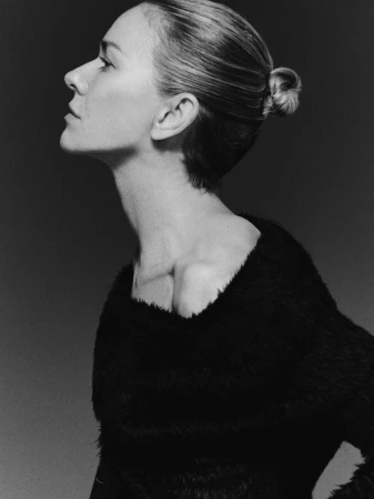 Monochrome portrait of a woman in profile with elegant hair, featuring a blurred background, black clothing and soft studio lighting.