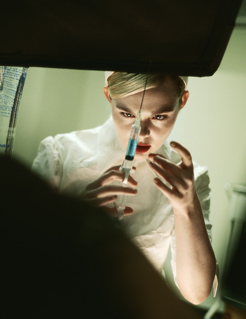 Woman in white nurse's uniform holds syringe with blue liquid in an indoor healthcare setting with subdued lighting, emphasizing medical theme.