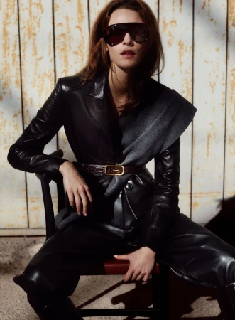 Model Coline Leclere wearing a black leather jacket and sunglasses seated on a chair for Vanity Fair Italia