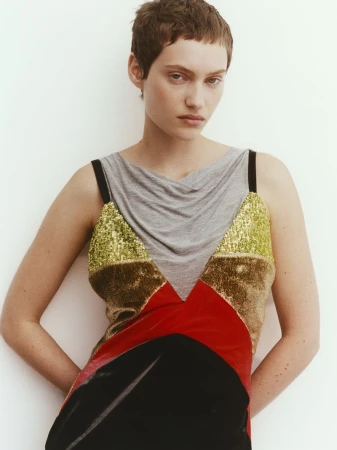Model Greta Hofer posing in a colorblock sequin and velvet dress against a white studio backdrop.