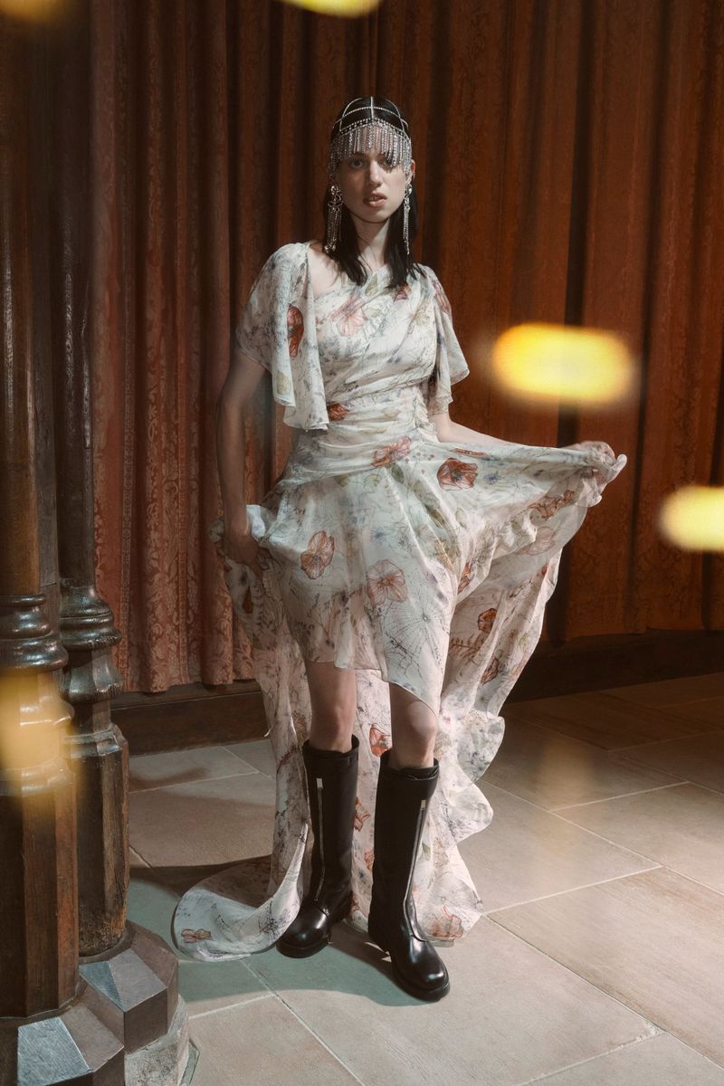 A fashion photo features a woman in a floral dress and black boots, accented by a jeweled headpiece, posing indoors with golden light.
