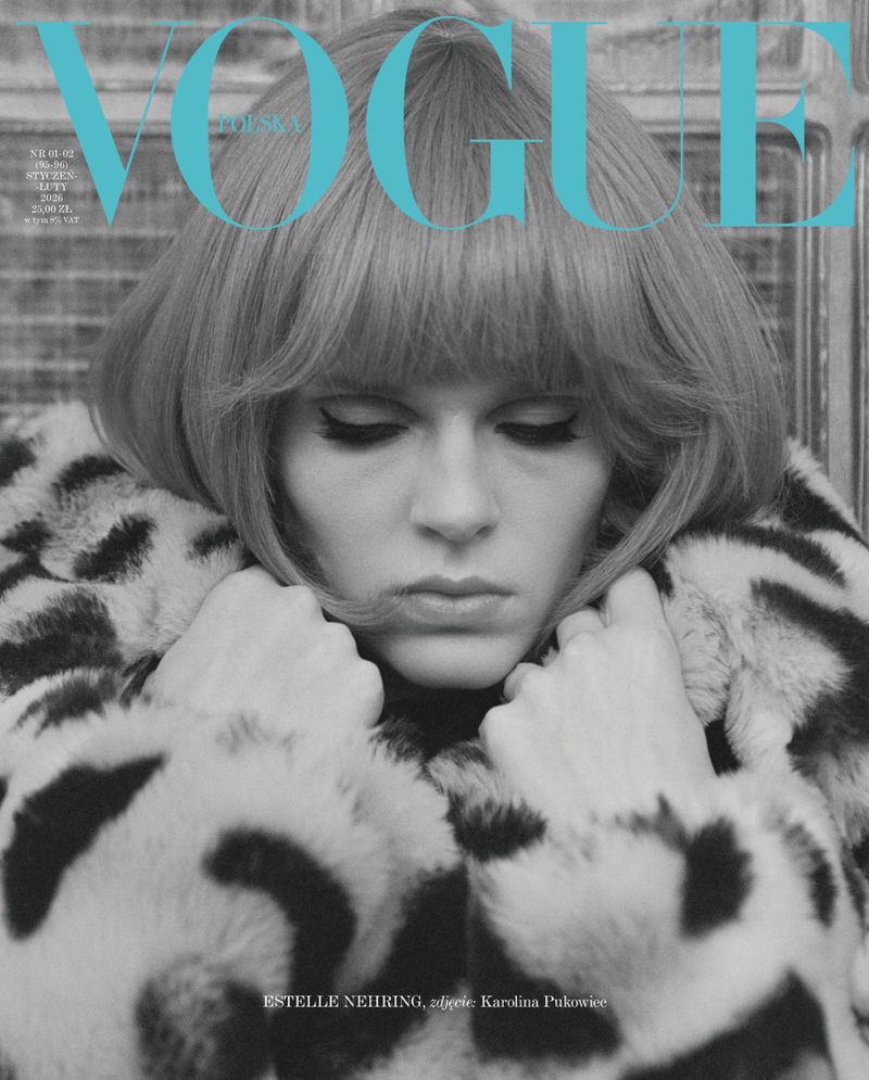 Black and white Vogue cover featuring a woman in a patterned coat looking down, with the magazine's name in blue at the top.