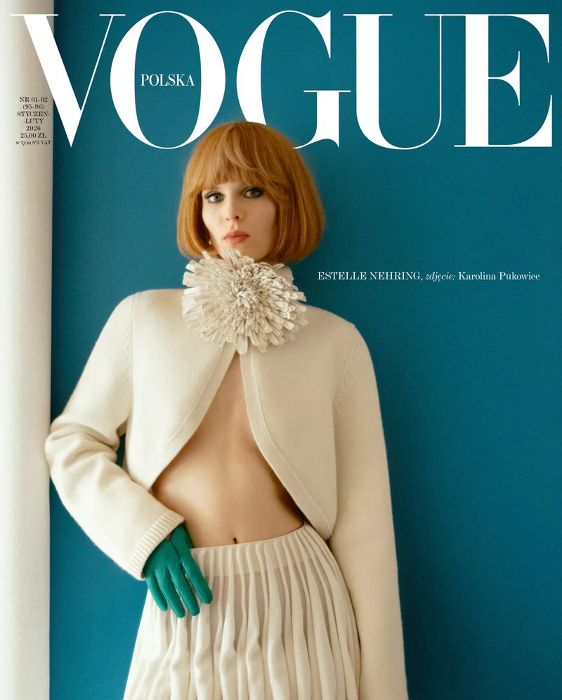 Vogue Polska cover featuring a female model with auburn hair, an off-white sweater and skirt, and green gloves, set against a teal backdrop.