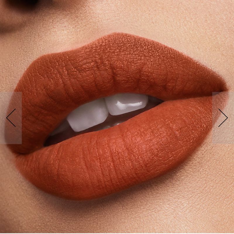 Macro close-up of an adult female's face featuring bright orange lipstick, pale skin, and white teeth in a studio setting.