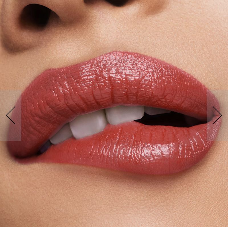 Close-up of a person's mouth with pink glossy lipstick highlighting the lips and visible white teeth, on a light skin background.