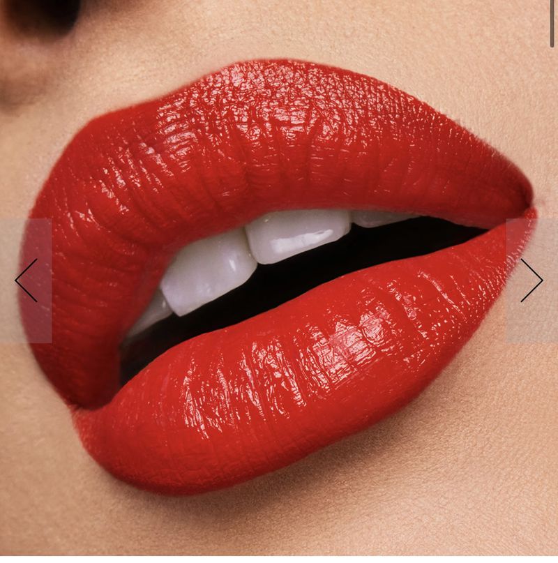 Macro beauty shot of bright red lipstick on woman's full lips, with visible white teeth, and fair skin. Focus on vivid color and texture.