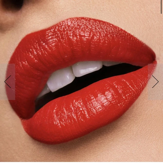 Macro beauty shot of bright red lipstick on woman's full lips, with visible white teeth, and fair skin. Focus on vivid color and texture.