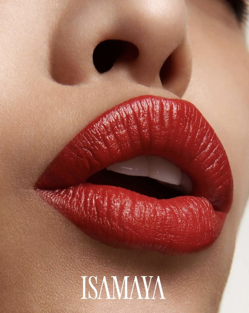 Close-up of a woman's face with vibrant red lipstick on full lips, highlighting the beauty and cosmetic features in a bright setting.