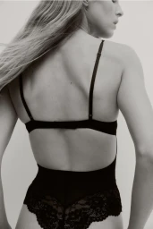 Model Abby Champion wearing black lace lingerie body against a clean light studio backdrop by photographer Pauline Suzor for H&M.