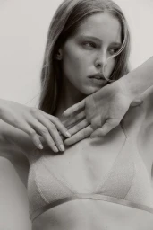 Model Abby Champion posing with hands near face wearing lingerie for H&M photographed by Pauline Suzor in black and white.