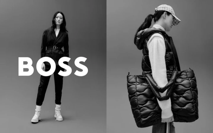 Black and white fashion shot of two Asian women modeling BOSS-branded clothing and accessories against a gray studio backdrop.