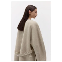 Model wearing a beige woolen wrap coat with a belt against a clean white seamless studio background.
