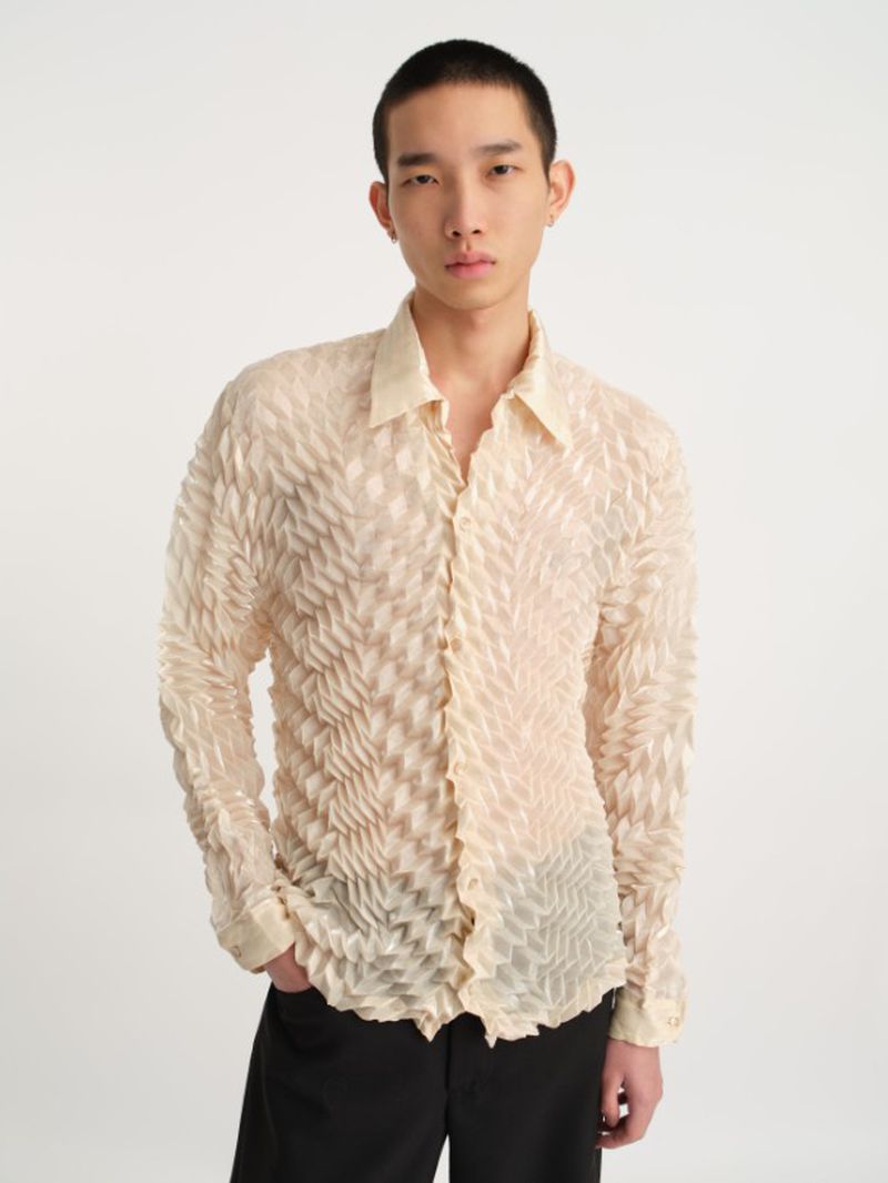 Portrait of an Asian adult male in a patterned button-down shirt and black pants, posing in front of a neutral studio backdrop.