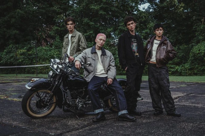 Four models posing outdoors with a vintage motorcycle for Harley Davidson campaign