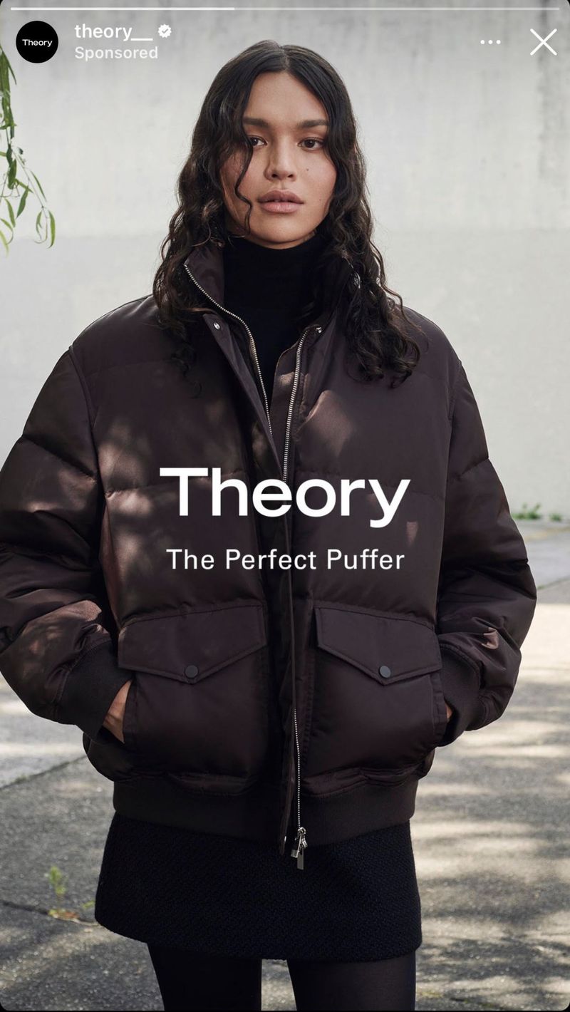 Portrait of a woman wearing a brown puffer jacket with dark hair, shot outdoors with visible text overlay.