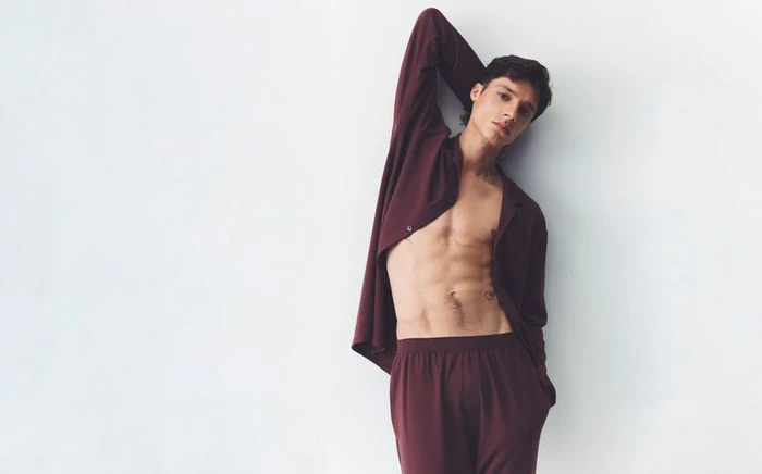 Model Aboubakar Konte in a burgundy shirt and trousers posing against a clean white background for Calvin Klein.