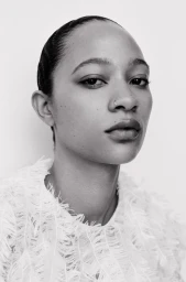 Close-up portrait of model Selena Forrest wearing a textured white garment against a seamless background.