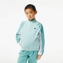 Young boy wearing a mint green and white athletic tracksuit against a clean white background.