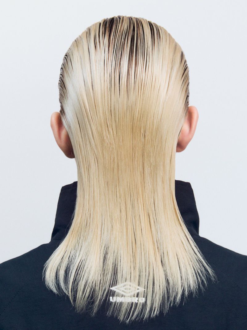 Blonde, shoulder-length hair styled sleek and straight, seen from the back, against a plain white background, featuring an Umbro jacket.