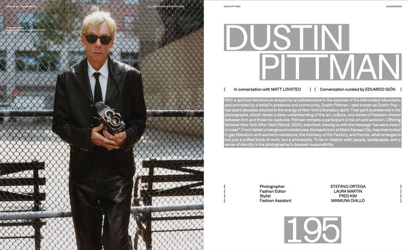 Mature blond man in leather jacket, tie, and sunglasses posing with vintage camera in urban setting by chain-link fence on magazine page.
