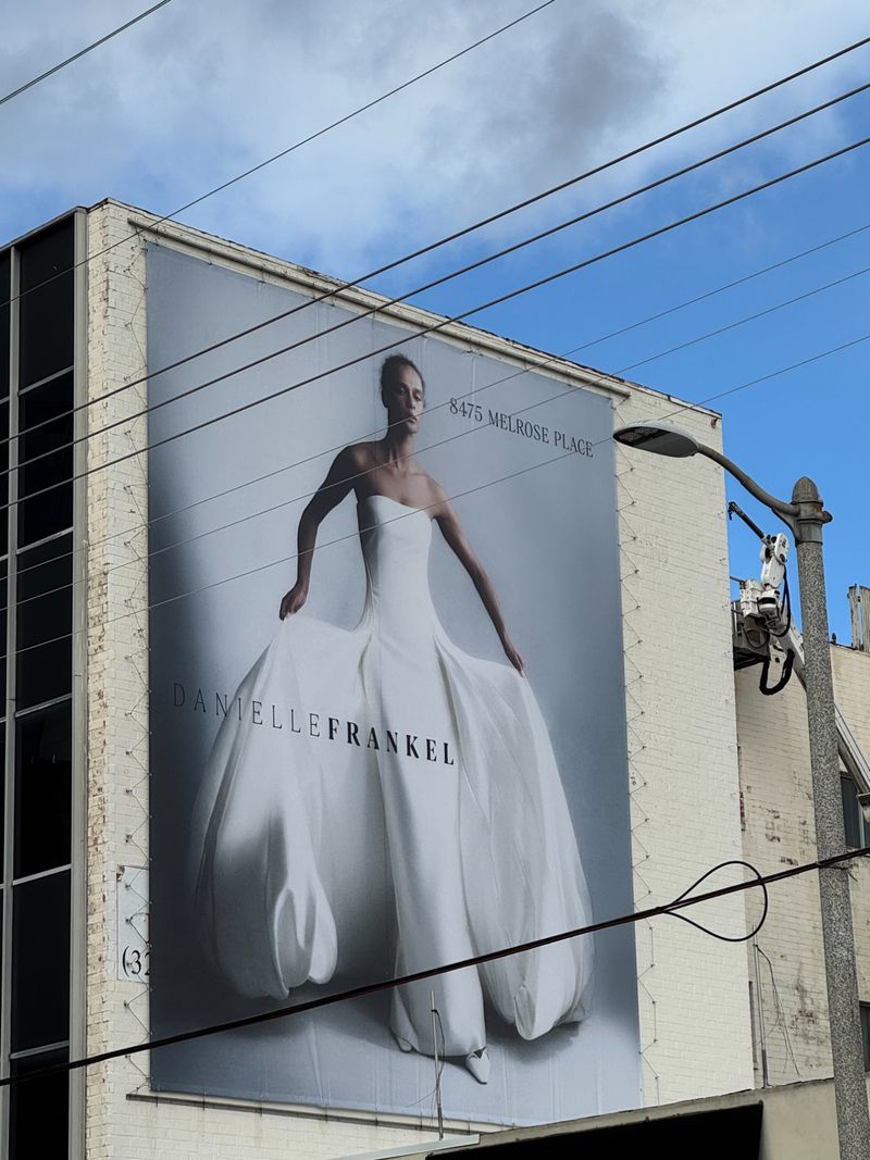 Large outdoor Danielle Frankel billboard mounted on a building exterior featuring a model posing in a white strapless gown.