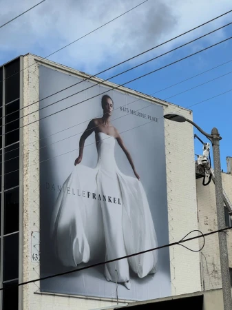 Large outdoor Danielle Frankel billboard mounted on a building exterior featuring a model posing in a white strapless gown.