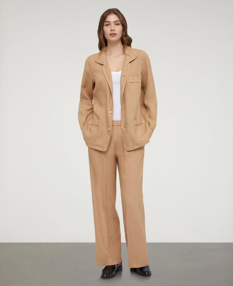 Full shot of a woman in a beige blazer and pants. Neutral studio background. Fashion, style, and modern professional concept.