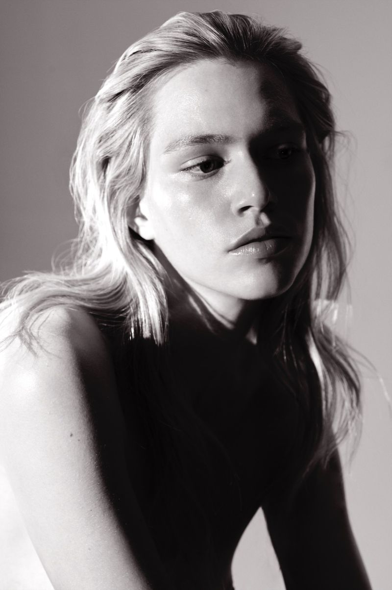Close-up portrait of a young adult woman with blonde hair and soft lighting in a studio environment, showcasing beauty and photographic art.