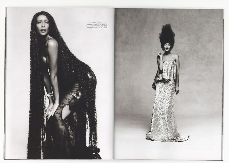 Black and white full shot of two women, one with waist-long hair and lace dress, the other in a full-length gown with large hair.