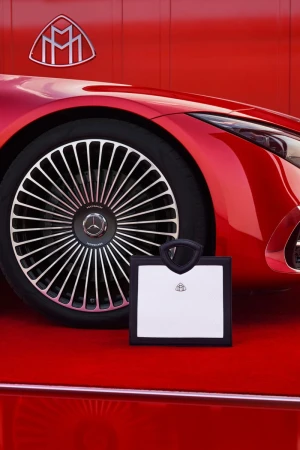 Red Maybach automobile wheel and front panel detail with logo, displayed on a matching red surface for a luxury automotive advertisement.