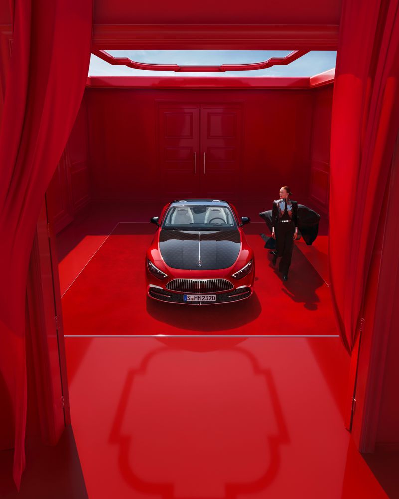 Elegant red Mercedes-Benz Maybach in a matching red showroom, complemented by a stylishly dressed woman in dark attire.
