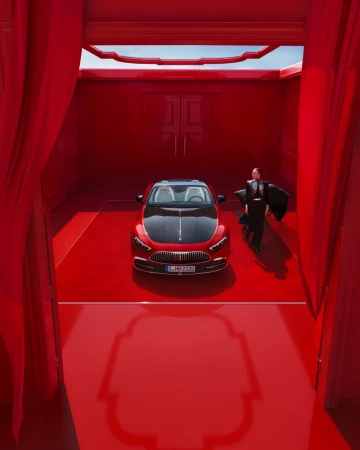 Elegant red Mercedes-Benz Maybach in a matching red showroom, complemented by a stylishly dressed woman in dark attire.