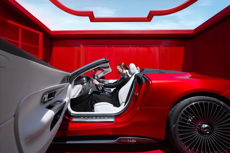 Red and white Maybach convertible car with a woman driver in a red interior, emphasizing luxury and automotive design.