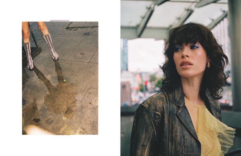 Fashion photo of a brunette woman in jacket and yellow top with boots reflected in a wet street in an urban setting.