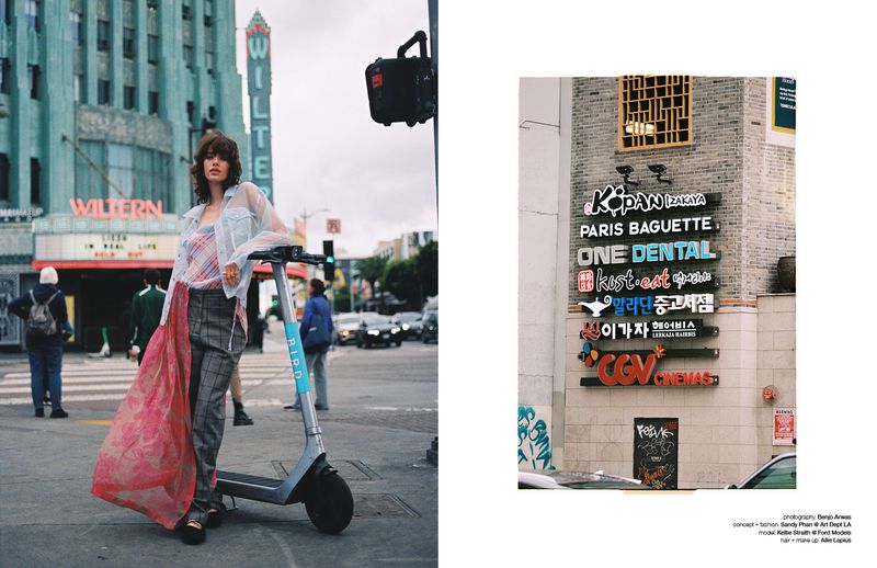 A young woman in fashionable clothes stands beside an electric scooter in front of the iconic Wiltern Theatre in Los Angeles on an overcast day.