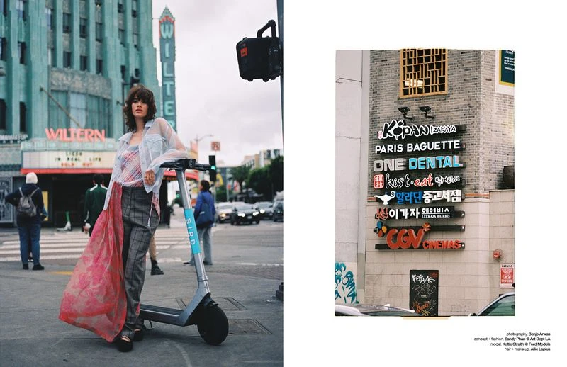 A young woman in fashionable clothes stands beside an electric scooter in front of the iconic Wiltern Theatre in Los Angeles on an overcast day.