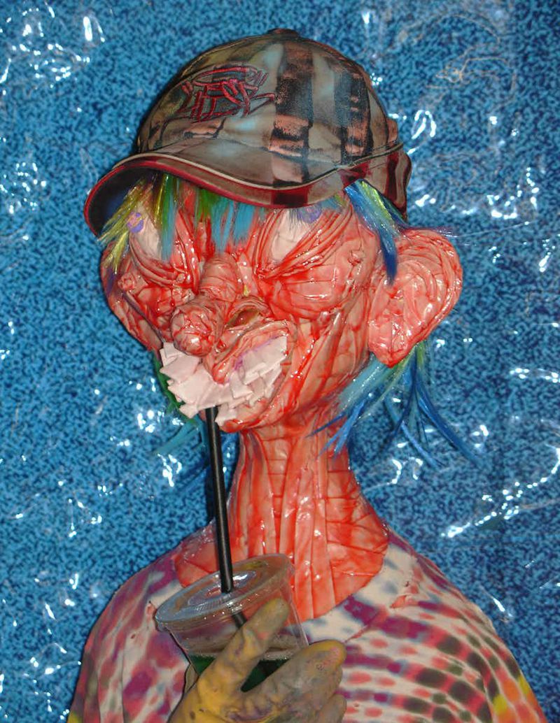 Unique portrait of a person-like mannequin wearing a tie-dye shirt and hat, holding a drink with a straw, against a blue backdrop.