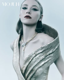 Model wearing a gold sequined dress and serpentine necklace against a plain grey backdrop for Mojeh Magazine