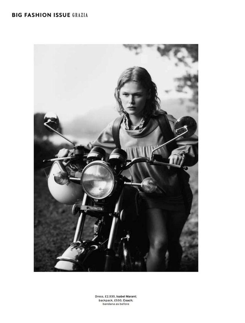 A woman poses with a vintage motorcycle on a rural road, wearing a mini-dress and backpack in a black and white fashion editorial.