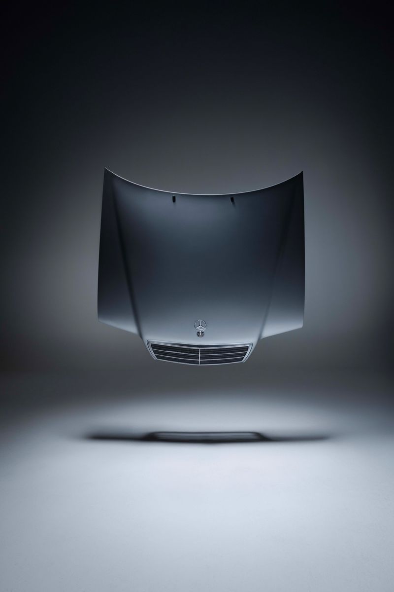 Automotive product shot of a silver car hood floating in a grey gradient studio with soft lighting and a shallow depth of field.
