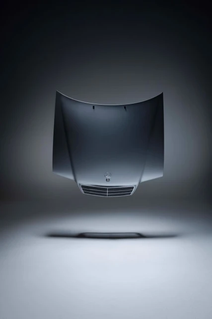Automotive product shot of a silver car hood floating in a grey gradient studio with soft lighting and a shallow depth of field.