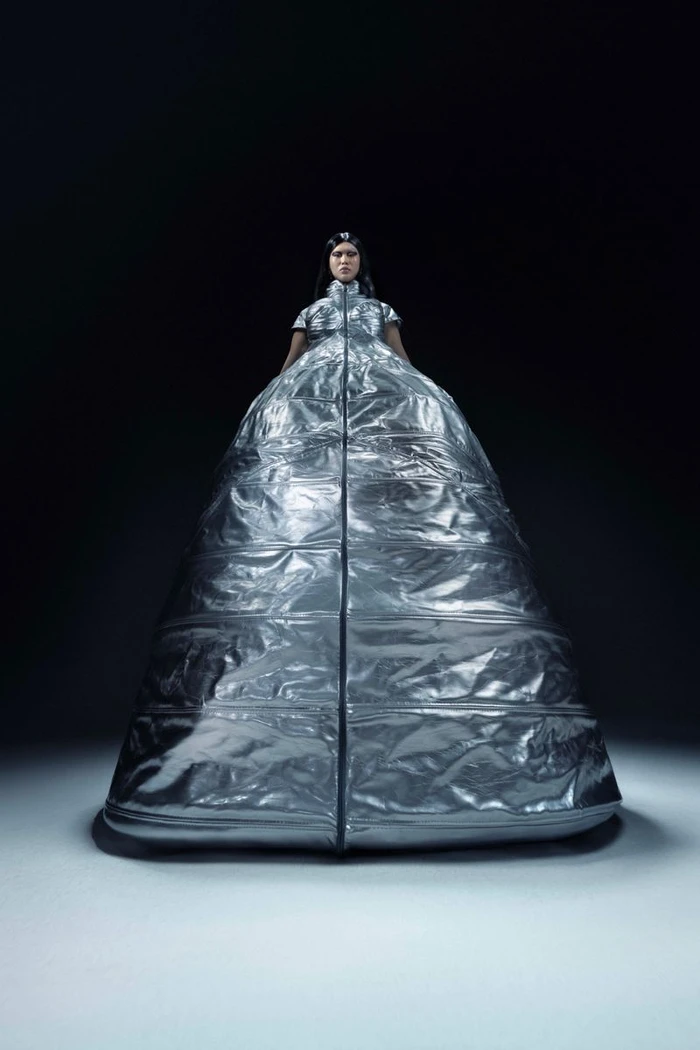 Model wearing a voluminous metallic silver quilted gown against a dark background in an editorial portrait for Numero Netherlands.