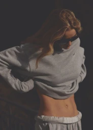 Rosie Huntington-Whiteley wearing dark sunglasses and a grey crewneck sweatshirt with matching sweatpants in warm sunlight.