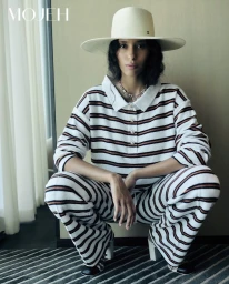 Model crouching wearing a striped polo outfit and wide-brimmed hat in an editorial portrait for Mojeh Magazine.