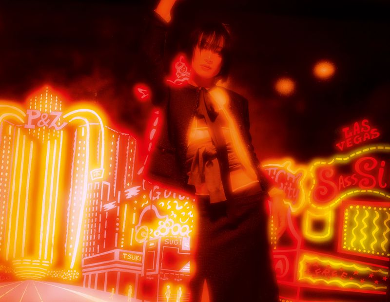 Woman in stylish black outfit striking pose in front of vibrant neon city lights for a fashion-forward and visually striking image.